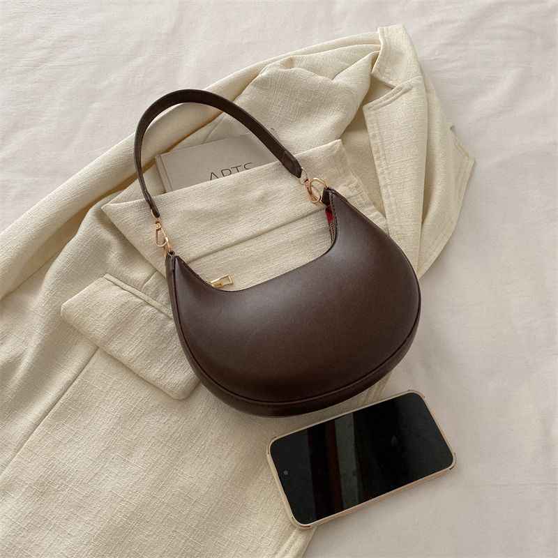 Sac demi-lune brun associé à une veste écrue